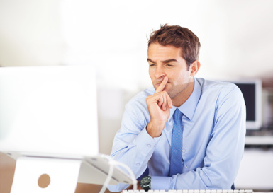 Man in business attire sitting at a desk with a confused look