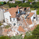 Large white house with collapsed brick roof and structural damage